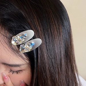 Pair of heart-shaped iridescent crystal hair clips worn on side hair for women