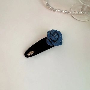 Close-up of black velvet hair clip with blue denim rose and gold metal detailing