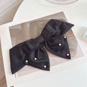 Elegant large black satin bow hair clip with white pearl accents on white background