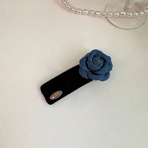 Detail of vintage denim rose and velvet hair clip with a small gold engraved plate