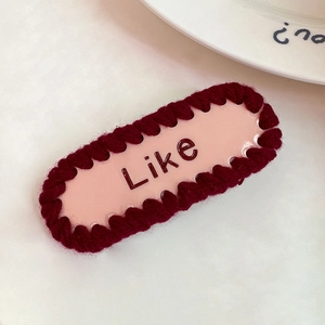 Détail d'une pince à cheveux rose avec texte Like et bordure rouge au crochet fait main