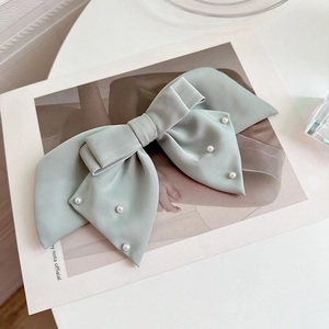 Elegant mint green satin bow hair clip with pearls on a minimalist background