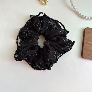 Detail of black mesh scrunchie with silver grid patterns and beaded edge decoration