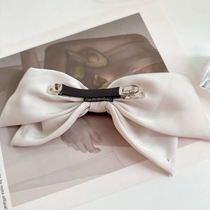Detailed macro view of the premium white satin bow hair clip with sturdy silver metal spring