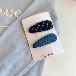 Haarklammern für Kinder mit blauem Karomuster Stickerei auf einer Karte vor blauem Stoff