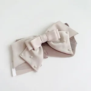 Elegant cream satin bow hair clip with pearl embellishments for women on white background