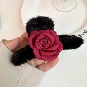 Detailed view of elegant plush flower hair claw with a red fabric rose and black fur texture