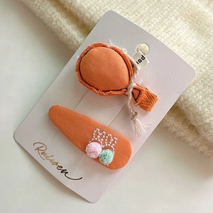 Dettaglio di fermagli per capelli per bambine con ricamo a coniglio e piccoli pompon colorati