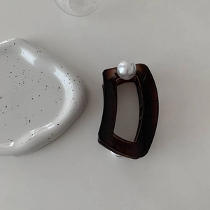 Détail d'une grande pince à cheveux ambre translucide avec une perle blanche décorative