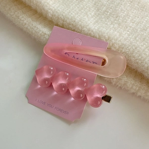 Détail de barrettes à cheveux roses mates en résine sur un fond en maille douce