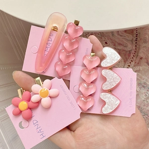 Détail de pinces à cheveux roses cœur et fleur avec texture pailletée sur carte