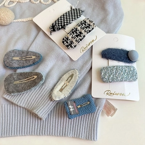 Detailaufnahme handgefertigter geometrischer Haarklammern aus Tweed und Plüsch auf Strick