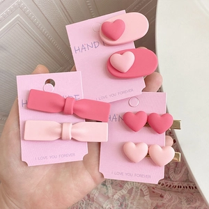 Gros plan d'un lot de barrettes à cheveux roses avec cœurs et nœuds sur cartes