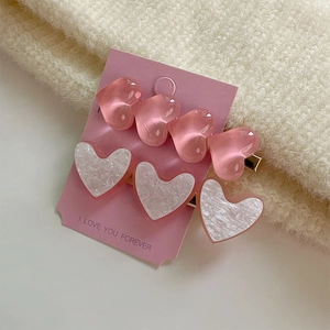 Détail de pinces à cheveux coeur rose avec textures translucides et marbrées sur carte