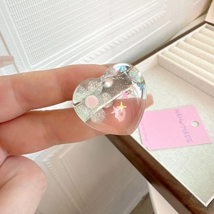 Handmade clear resin heart ring with colorful glitter stars and a pink flower
