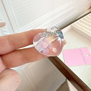Detail view of handmade pink glitter heart hair clip with colorful star sequins