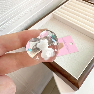 Macro shot of transparent heart hair clip with white bear and colorful stars detail