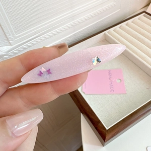 Detail of pink glitter hair clip with purple butterfly sequins and hand-made craft style