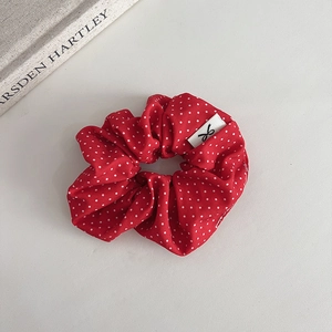 Retro red scrunchie with white polka dots and decorative label on grey background