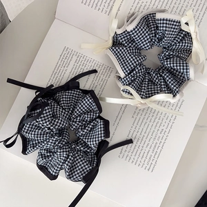 Preppy black and white plaid scrunchie with a delicate bow on a vintage book