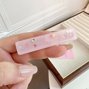 Detail of pink resin hair clip with glitter butterfly and star sequins for girls
