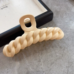 Vue détaillée d'une pince à cheveux mate crème sur marbre avec un design minimaliste élégant