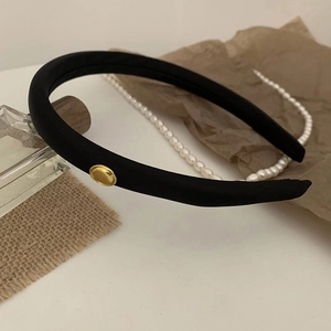 Retro black padded headband with gold button detail shown from a 45-degree angle