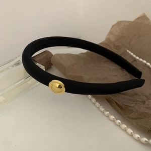 Close-up of black fabric headband with vintage gold button detail and luxury background