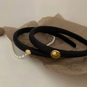 Elegant set of two black padded headbands with gold buttons on vintage paper background