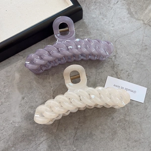 Grandes pinces à cheveux tressées en lilas et crème sur fond de marbre gris
