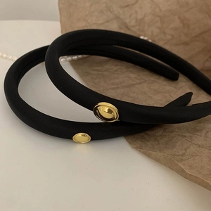 Detailed macro view of two black padded sponge headbands featuring round gold metal buttons