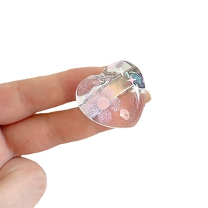 Sweet heart-shaped hair clip with pink glitter and star elements held by hand