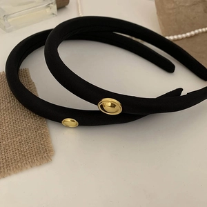 Close-up of black padded headbands with golden vintage buttons on rustic background