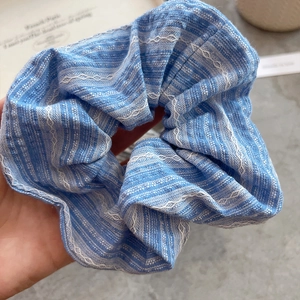 Detailed macro view of blue striped cotton scrunchie with white wavy embroidery texture