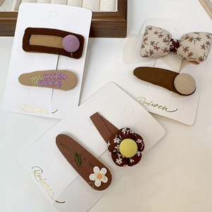 Détails de broderies florales et nœuds sur barrettes BB aux tons chauds de terre