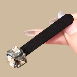 Dettaglio di un fermaglio per capelli nero con decorazione in cristallo a cubo sfaccettato