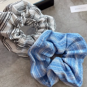 Detailed close-up of blue and white striped cotton scrunchies on marble background