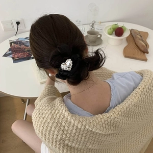 Dettaglio di un elastico nero a pieghe con un grande strass a cuore in un ambiente lifestyle
