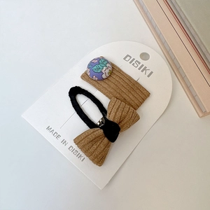 Détail de la barrette à fleurs et du nœud en velours côtelé marron sur carte blanche