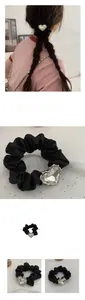 Dettaglio di scrunchie in raso nero largo 3cm con cristallo a forma di cuore oversize
