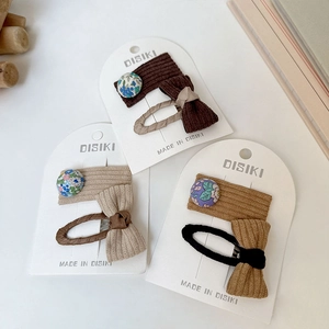 Détail de barrettes BB en tissu avec bouton floral et nœud aux tons terreux