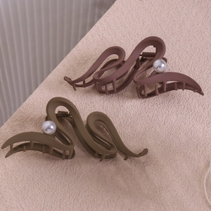 Détail de pinces à cheveux ondulées en marron mat et vert olive avec perle décorative