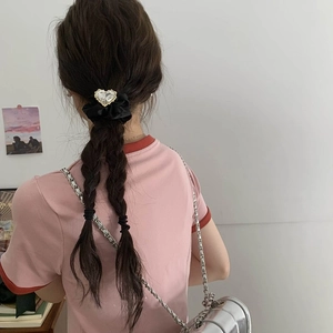 Dettaglio dell'elastico per capelli in raso nero con cristallo a forma di cuore indossato