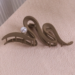 Détail macro d'une grande pince à cheveux ondulée marron mat avec perle élégante
