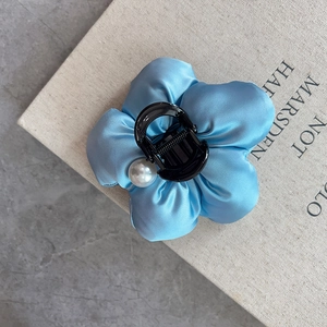 Elegant blue satin flower hair claw clip with pearl detail on grey marble surface