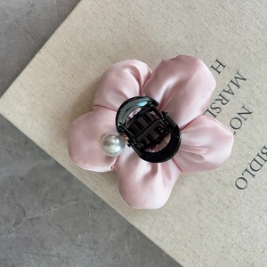 Elegant pale pink satin flower hair claw clip with pearl detail on marble background