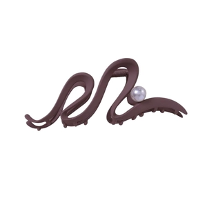 Pince à cheveux mate marron en forme de vague avec perle sur un fond blanc épuré