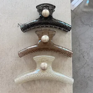 Detail of vintage textured large hair claws with pearls in black, coffee, and beige colors
