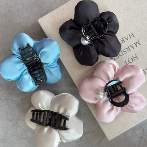 Detailed close-up of elegant satin flower hair claws in blue, pink, black, and beige colors