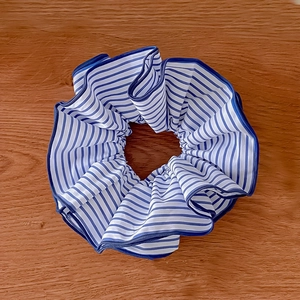Chouchou à rayures bleues et blanches avec bordure marine sur fond en bois foncé